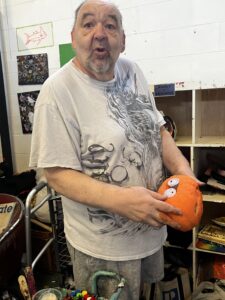 An Excited bill carpenter rearranging his Halloween display.(holding pumpkin)